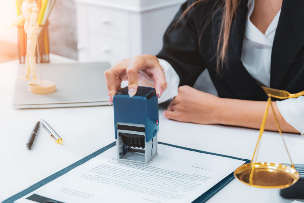 Female notary stamping document agreement at table close up