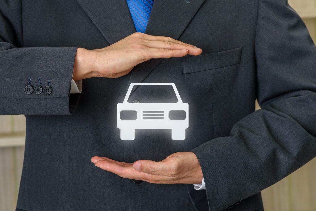 Businessman broker or saleman uses hands to protect a car or automobile, depicts protecting unexpected repair bills or situation