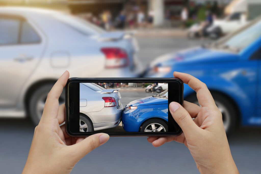 Close up hand holding smartphone and take photo at The scene of a car crash and accident, car accident for car insurance auto claim.