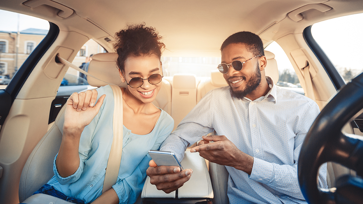Young couple driving car and using digital map on smartphone, panorama. cheap car insurance in frankford
